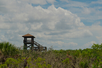 Wide view up to the bright blue sky with white puffy clouds of the covered observation tower in a...