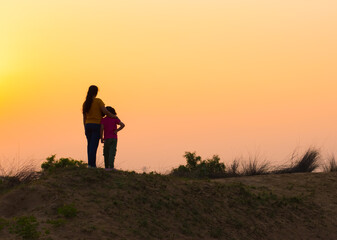 Fototapeta premium a girl with her mother enjoying summer holiday by watching sunrise . Happy family