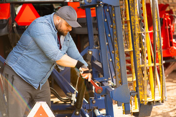 The farmer repairs agricultural machines