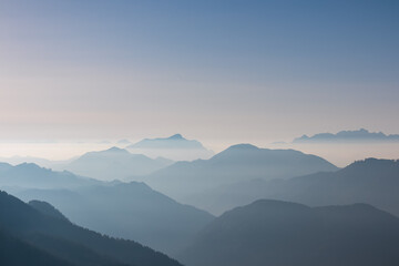 Serene alpine landscape at dawn in Gailtal Alpen, Carinthia, Austria, Europe. Silhouette of majestic hazy mountain ridges of Julian Alps. Peaceful tranquil atmosphere in Austrian Alps. Wanderlust