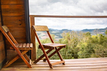 two wooden chairs on the porch of the country house with a view of the mountains on a cloudy day