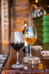 two wine glasses on wooden table red wine and white wine with bottle in the background in rustic country house