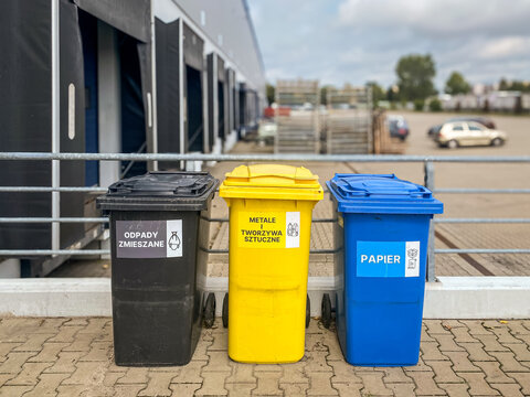 Kosze recyklingowe na terenie firmy, zarządzanie odpadami, ekologia, segregacja odpad&oacute;w, plastik, papier, tworzywa sztuczne, zmieszane. Trzy kosze na śmieci.