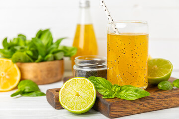 Diet detox cocktail with basil and chia seeds in a glass jar and a glass on a textured background....