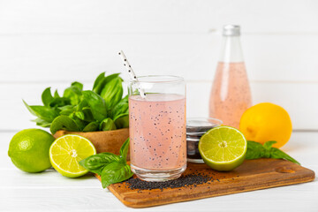 Diet detox cocktail with basil and chia seeds in a glass jar and a glass on a textured background....
