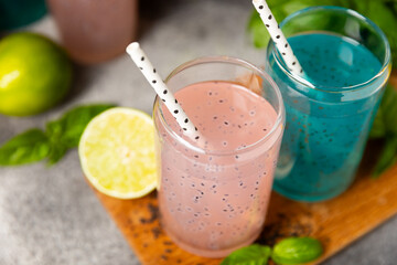 Diet detox cocktail with basil and chia seeds in a glass jar and a glass on a textured background....