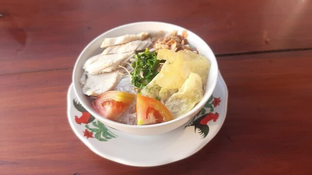 A bowl of soto ayam or chicken soup, typical Indonesian food on wooden table