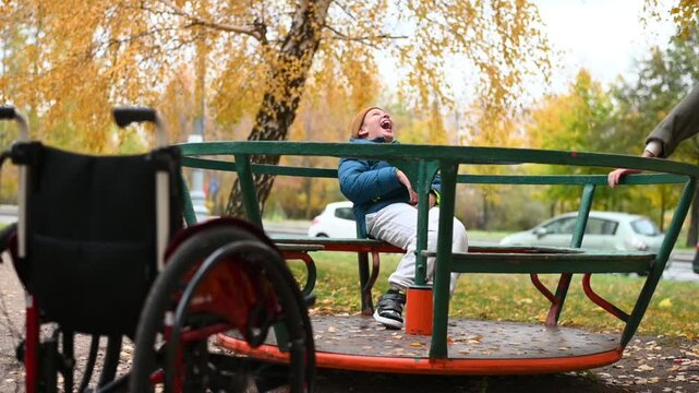 a 10-year-old disabled child in a wheelchair on the street with his mother for a walk. in autumn. High quality FullHD footage