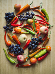 Vertical Flat Lay of Blue Grapes, Tomatoes, Apples and Colorful Chili Peppers on Wooden Table