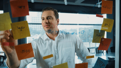 Portrait of professional male leader writing marketing idea on sticky notes. Caucasian businessman...