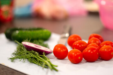 Fresh vegetables for salad cucumber tomatoes onion and dill with knife on the cutting board