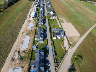 A new passive semi-detached housing estate has been built on the outskirts of a large city, featuring solar panels on the roofs and modern passive houses that comply with climate standards.