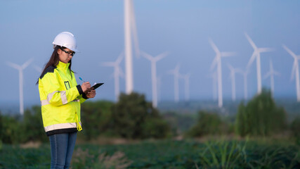 Two engineers working and holding the report at wind turbine farm Power Generator Station on mountain,Thailand people,Technician man and woman discuss about work