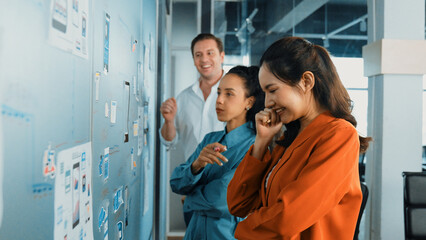 Portrait of group of businesspeople putting sticky notes on glass board. Professional business team brainstorming marketing strategy while stick notes on glass wall. Business meeting. Manipulator.