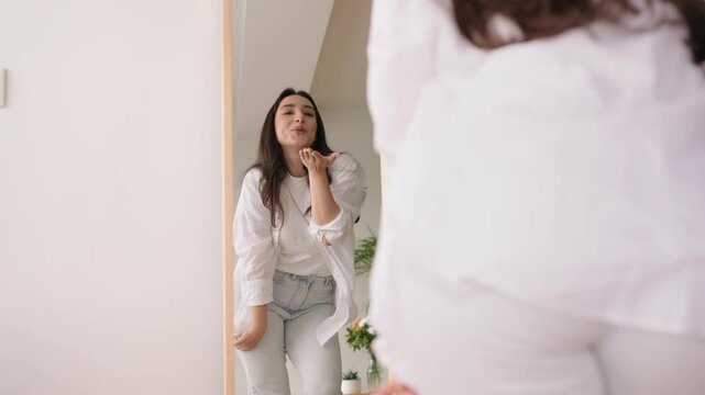 A plus size young woman is dancing joyfully in front of a mirror, showcasing self-love and radiating positivity with her spirited demeanor. - Powered by Adobe