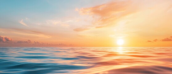 Fototapeta premium A large body of water with the sun setting, casting an orange glow over its surface, and clouds tinted pink and gold in the backdrop