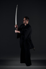 Samurai ninja warrior in kimono in attack pose with katana sword. dark room. sword shine. fighter. japanese culture