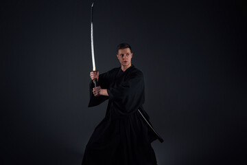 Samurai ninja warrior in kimono in attack pose with katana sword. dark room. sword shine. fighter. japanese culture