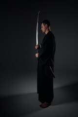 Samurai ninja warrior in kimono in attack pose with katana sword. dark room. sword shine. fighter. japanese culture