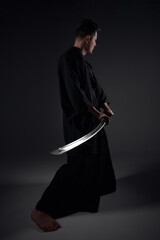 Samurai ninja warrior in kimono in attack pose with katana sword. dark room. sword shine. fighter. japanese culture