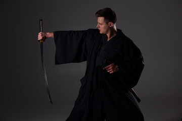 Samurai ninja warrior in kimono in attack pose with katana sword. dark room. sword shine. fighter. japanese culture