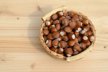 Hazelnuts in shell in a basket, wooden background, copy space for text