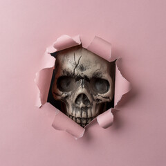 Skull looking through pink ripped paper. Minimal Halloween concept.