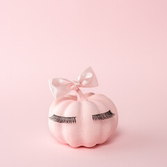 Pink Halloween pumpkin with pink bow tie on a pink background. Minimal Halloween spooky girl concept.