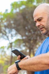 Man connecting phone to smart watch, outdoors.