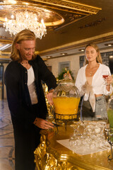 Man Pouring Juice into a Glass While Woman Holds Another Drink..