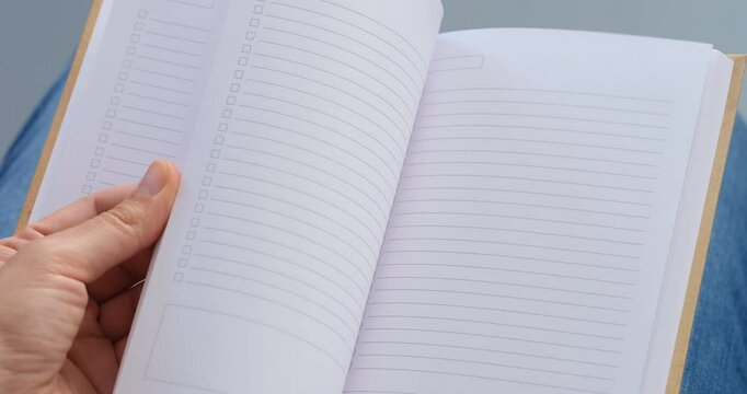 Woman flipping through the pages of the new day planner lying on her lap 