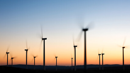 Obraz premium A row of wind turbines spinning against the backdrop of dusk, creating an abstract and atmospheric scene with blurred motion.