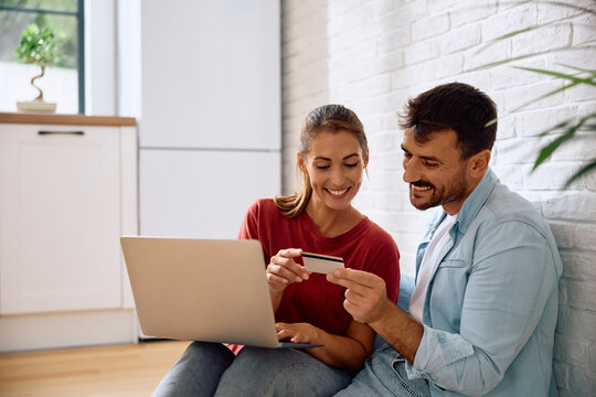 Happy couple using credit card and laptop while shopping online at home