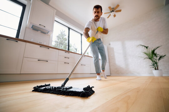 Close up of man cleaning parquet floor with a mop.