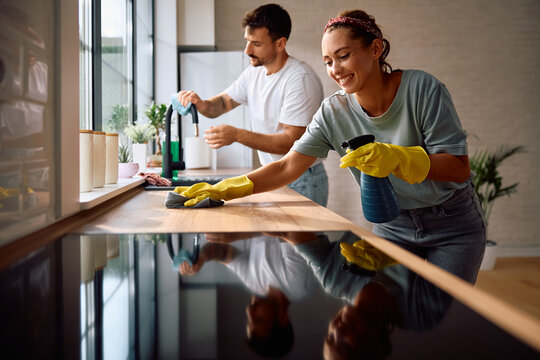 Happy woman cleaning  kitchen with her boyfriend.