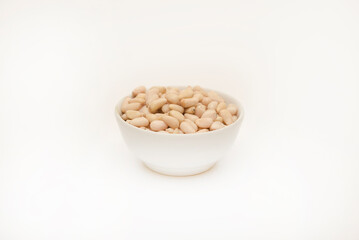 Pine nuts on a white plate. Hazelnuts.