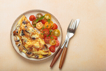 Mushroom omelette with cherry tomato salad on the side, served on a plate. Healthy breakfast or lunch top view, space for text