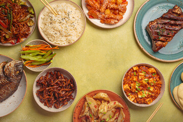 Variety of delicious chinese dishes on plates and bowls arranged on green background: kung pal...