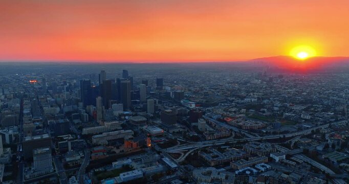 Sun hiding behind the mountain in gorgeous Los Angeles, California, the USA. Drone rising above the city view at sunset.