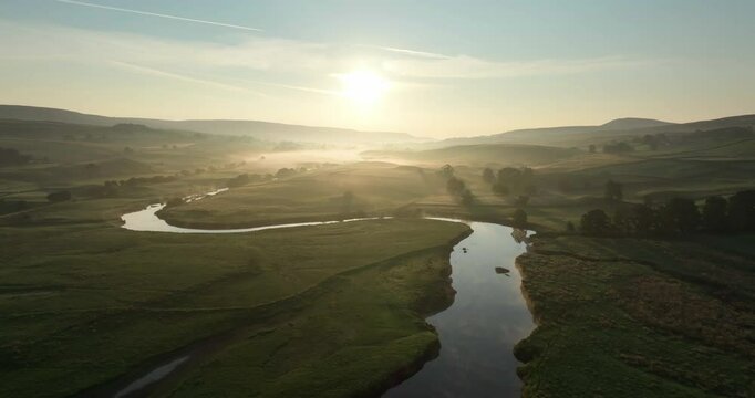 Flying over calm river in a misty valley