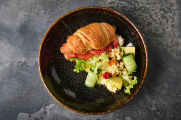 delicious salmon croissant sandwich, garnished and presented on a rustic, textured plate, showcasing a blend of flavors and textures