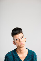 Transgender person, tired and thinking in studio for discrimination, anxiety and bored. Man, cosmetics and frustrated on white background space with identity crisis with makeup for aesthetic or pride