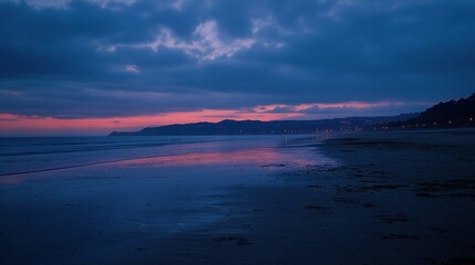 Fototapeta premium Serene beach at dusk with soft waves and a colorful sky reflecting on the water.