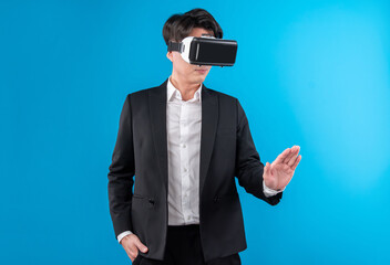 Asian businessman looking thorough VR while touching screen with connecting business world report in futuristic metaverse analyzing innovation technology virtual reality blue copyspace. Contrivance.