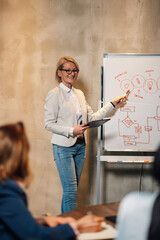 Senior businesswoman pointing on a whiteboard the statistic during a meeting
