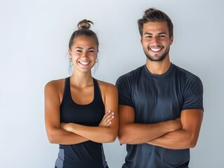 Young smiling man and woman in athletic wear standing on white background