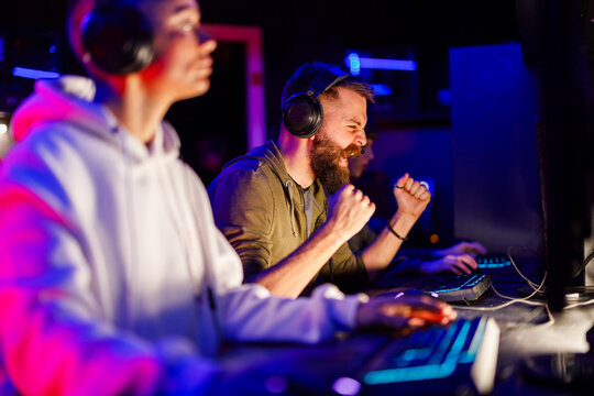 Gamer guy celebrating victory in video game while sitting in cybercafe