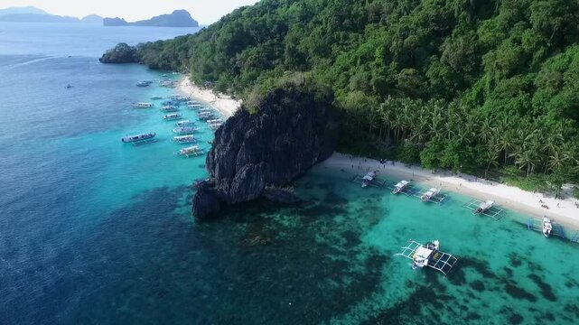 Seven Commandos and Papaya Beach in Palawan, Sightseeing Place. Tour A in El Nido, Philippines. Serene white sand beach with clear turquoise water, palm trees rock formations in Background. Drone