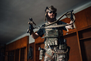 An airsoft player in camouflage uniform putting gun belt on.