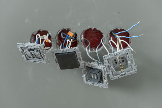 Electrical outlets are being installed in a wall, showcasing wires and connections during a home renovation effort